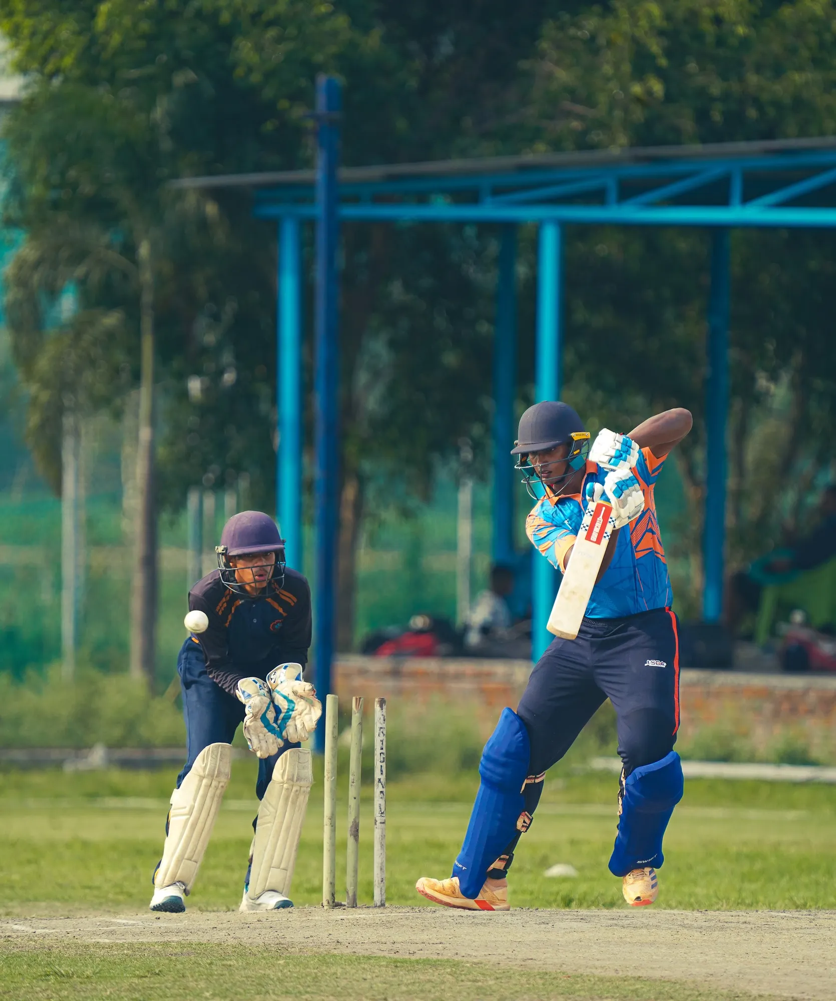 A batter shaping to play as the wicketkeeper waits behind the stumps