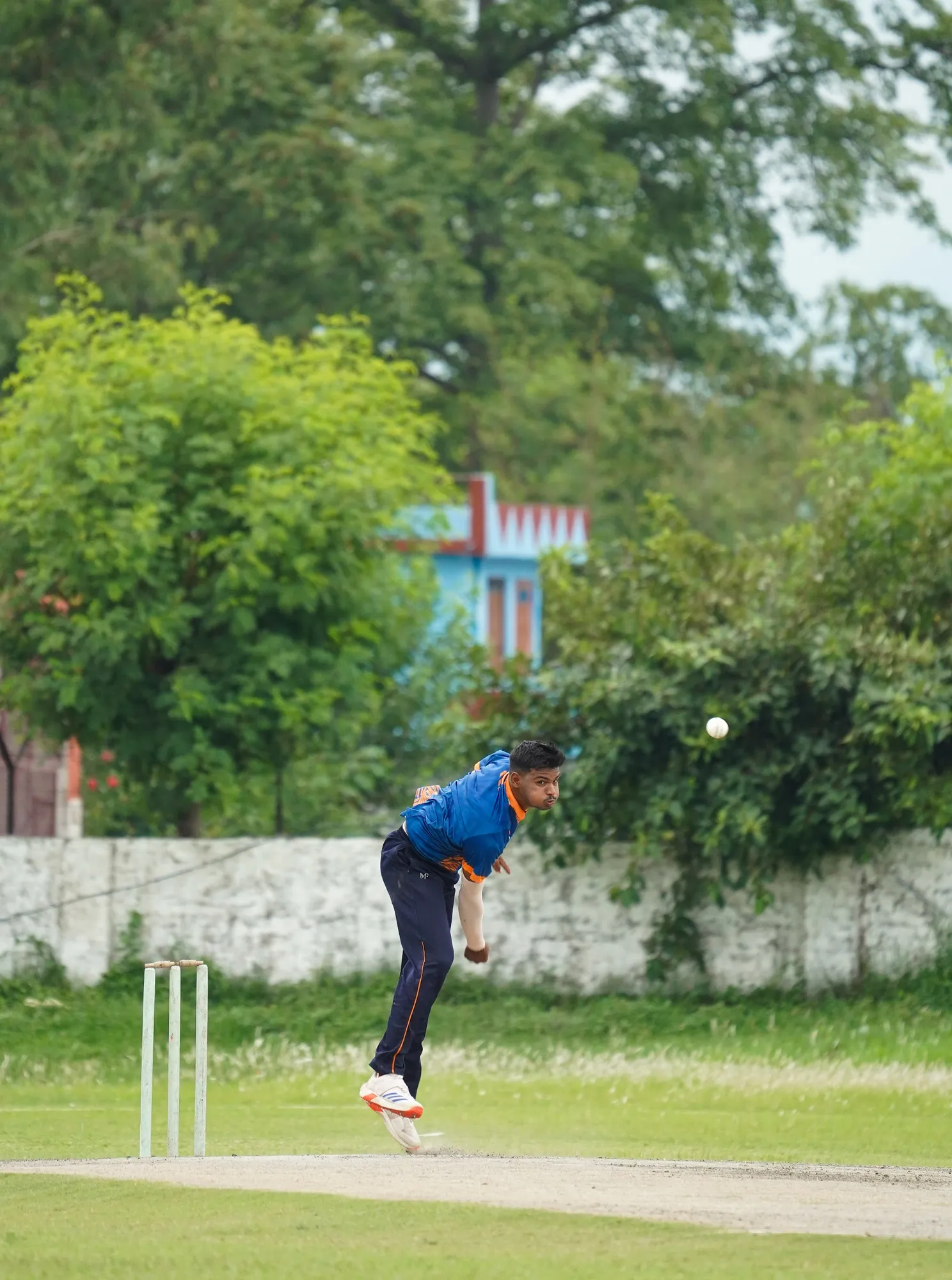 An SCA bowler releasing the ball, seen from across the ground