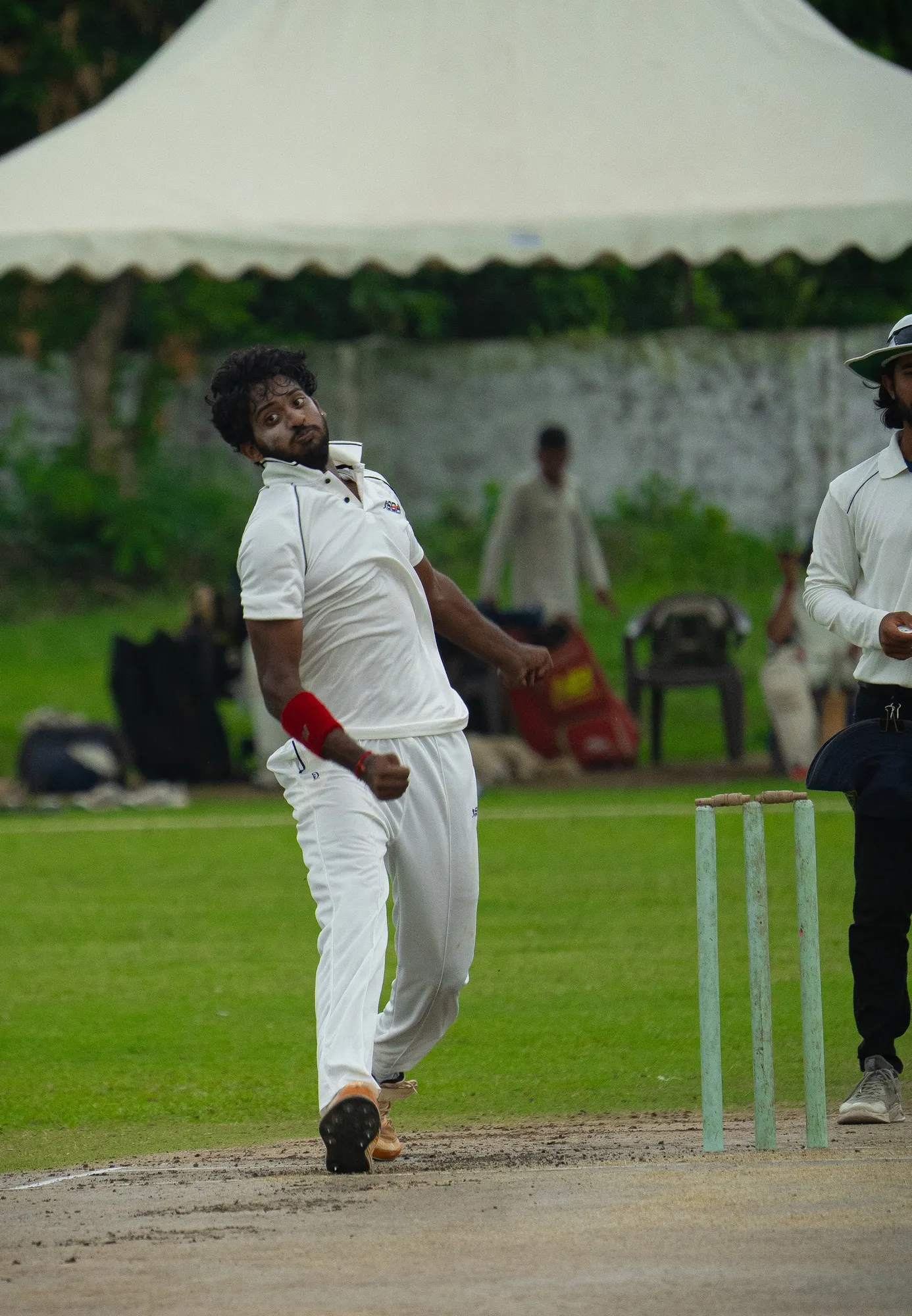 A bowler in whites running in past the umpire