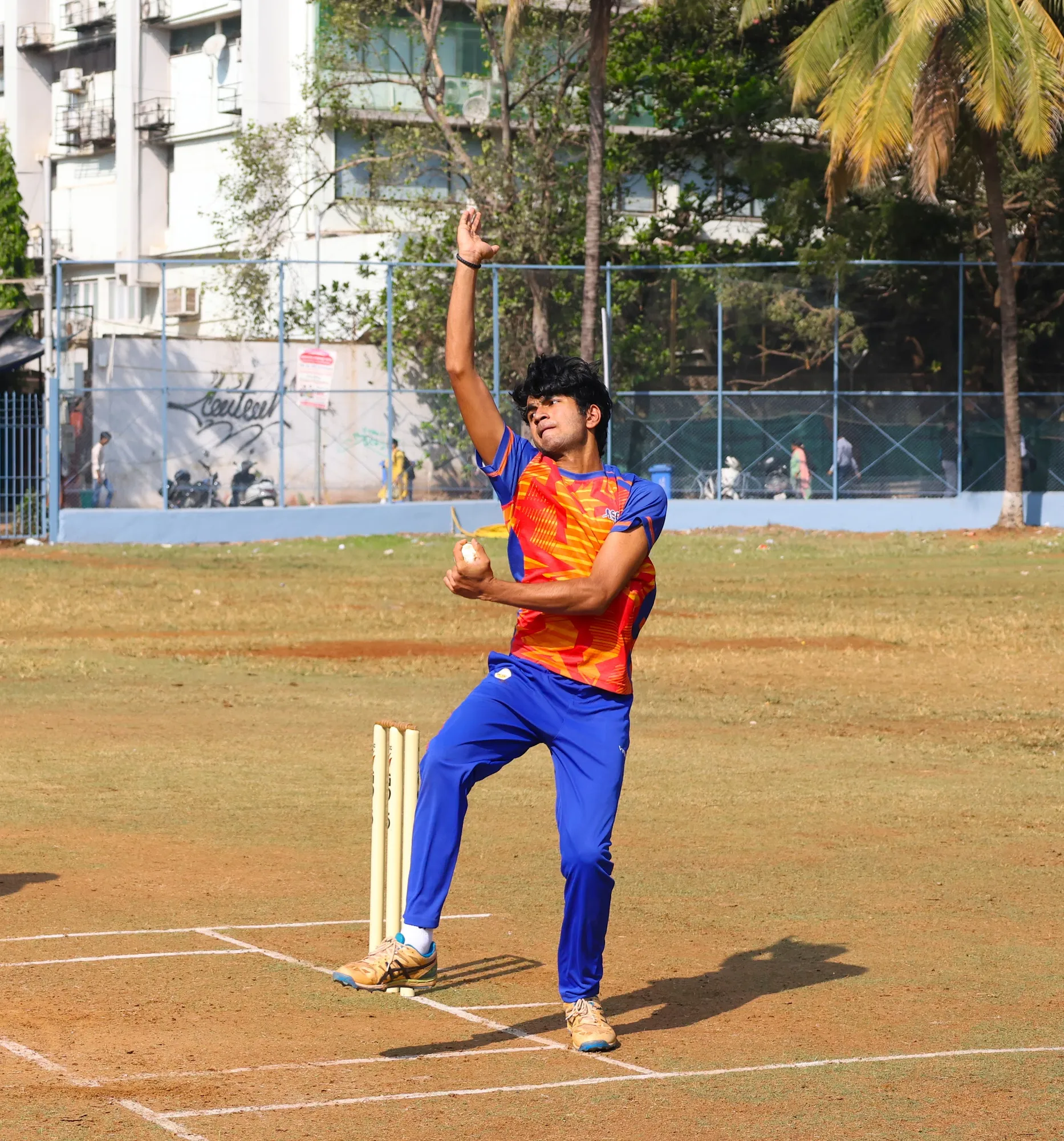 A bowler side on at the crease with his front arm raised