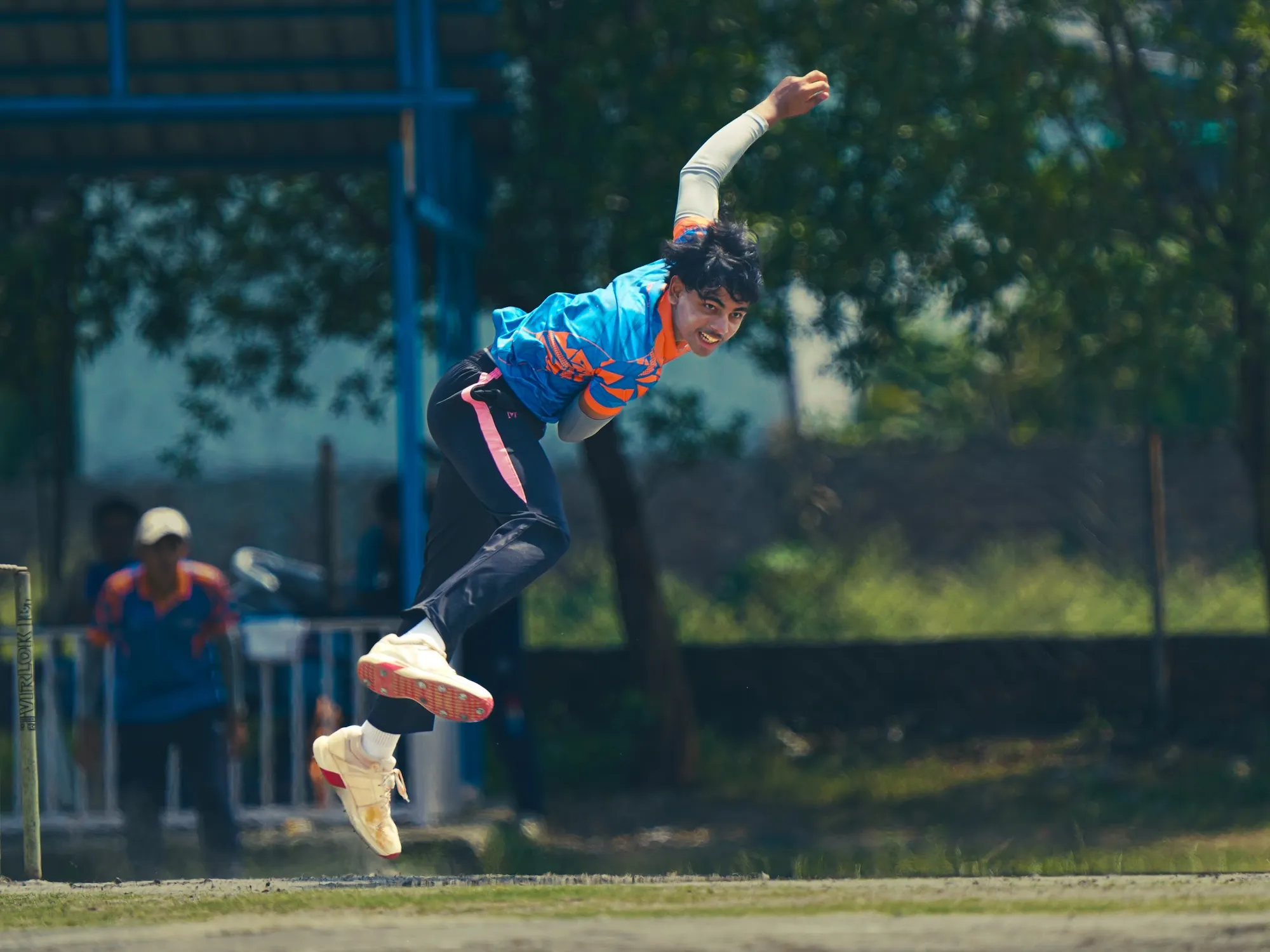 An SCA bowler airborne in his delivery stride